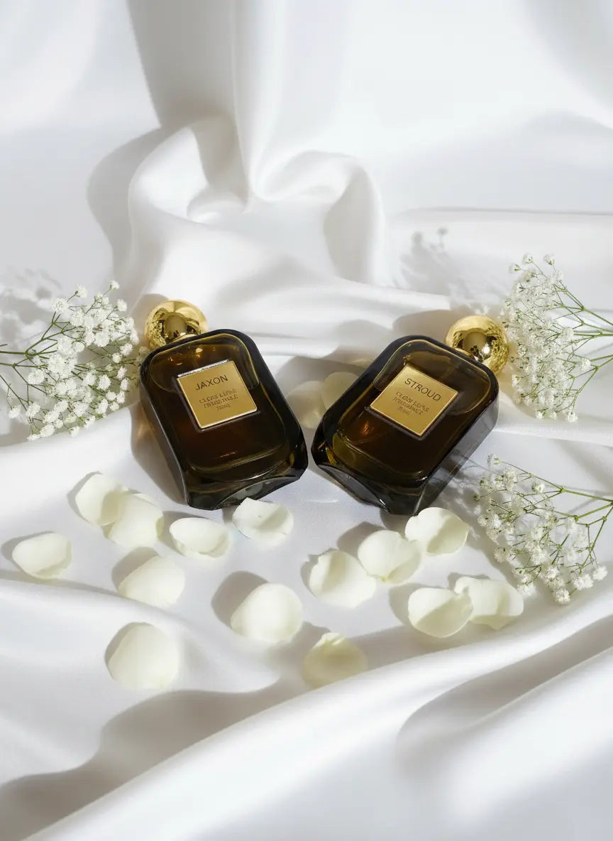 Jaxon and Stroud unisex perfume bottles on white fabric with flower petals and baby's breath